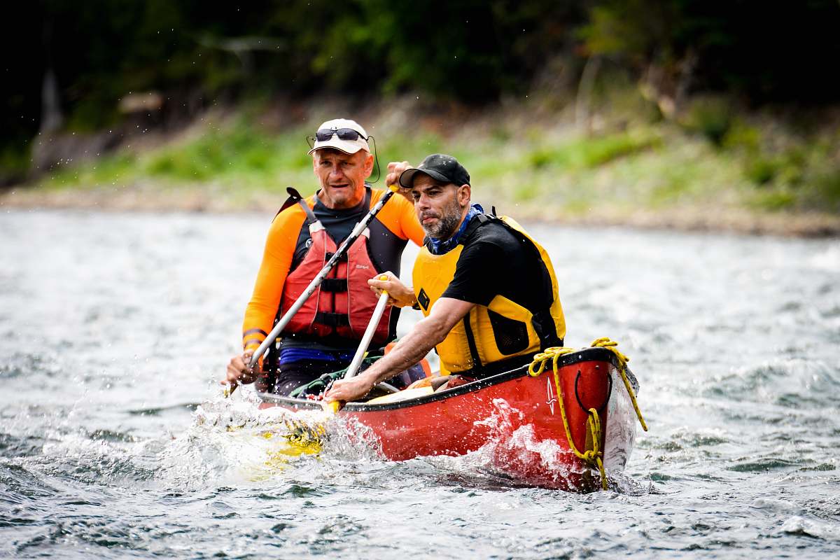 vessel two men riding on red canoe boat boat