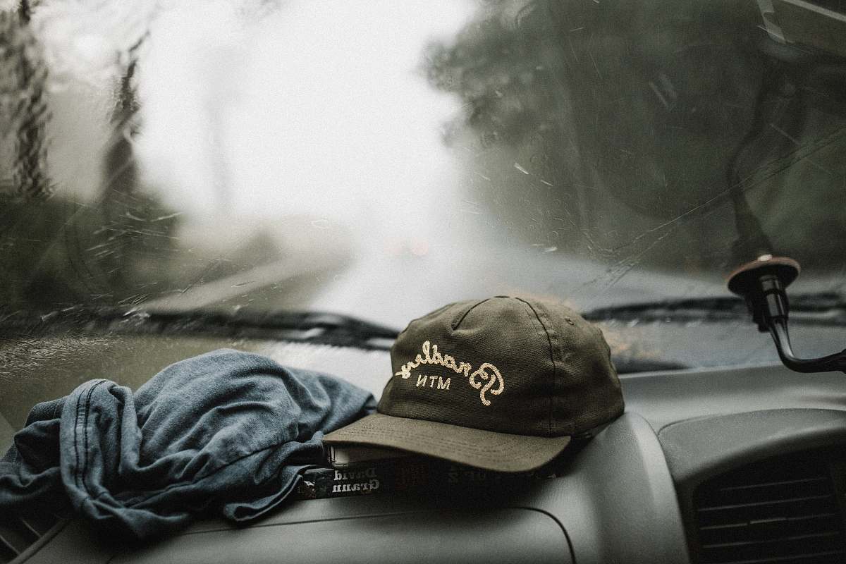 cap black and white baseball cap near grey shirt on top of glove compartment inside car trip