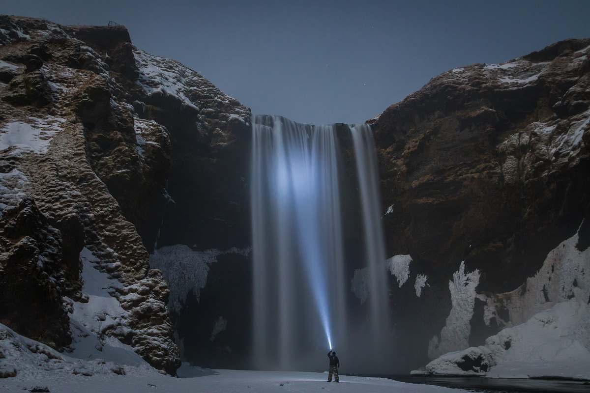 waterfall man standing in front of the waterfalls nature