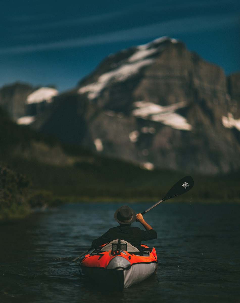 canoe man riding on inflatable kayak beside mountain kayak