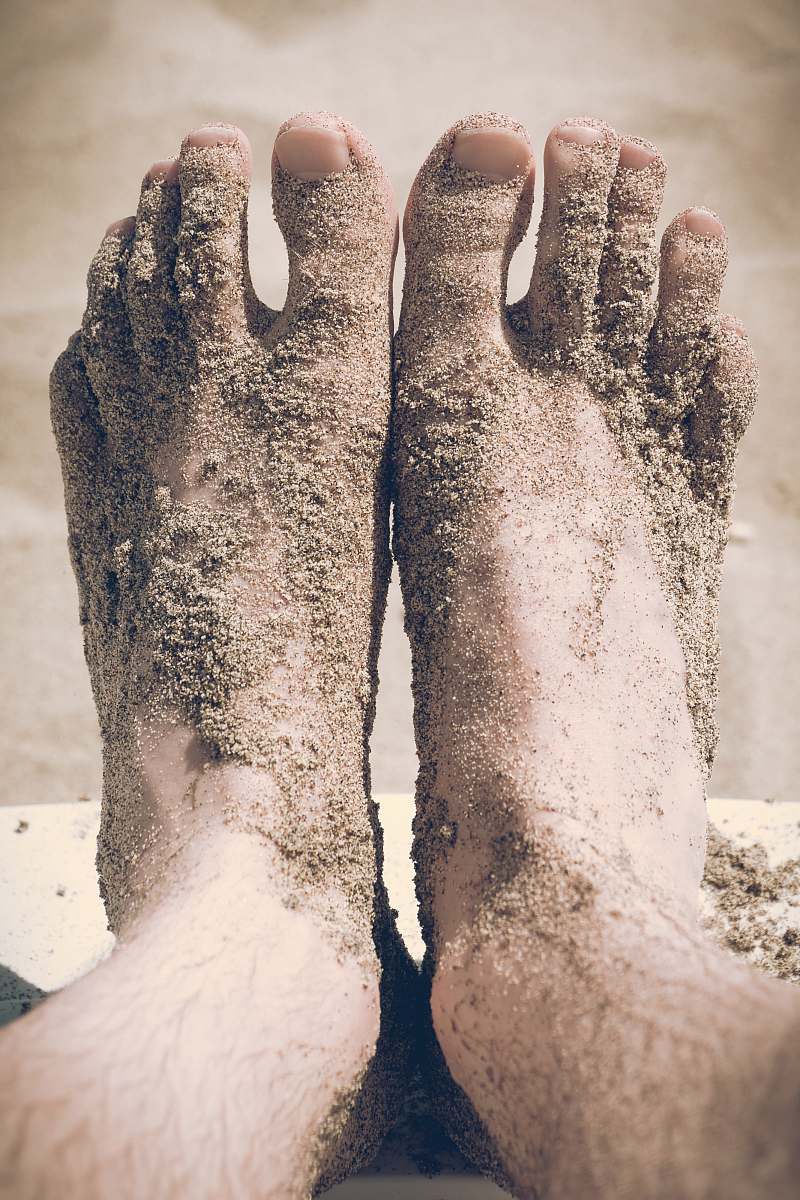 sand closeup photo of person's feet covered with sand foot