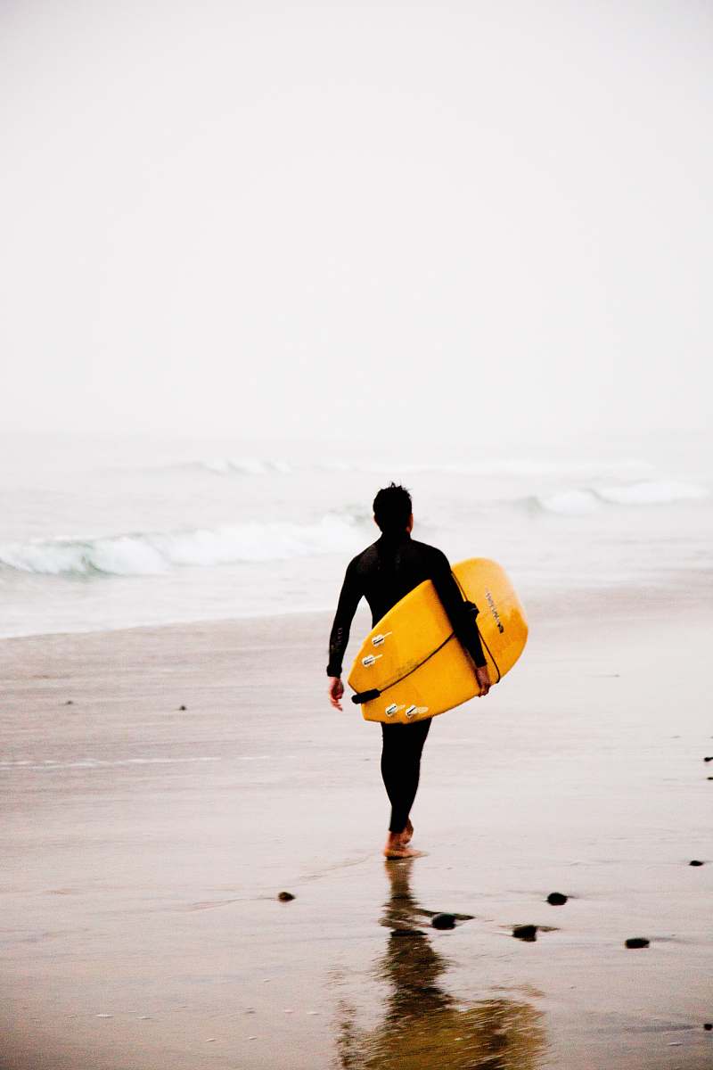 sea man holding yellow surfboard while walking on seashore during daytime surfing