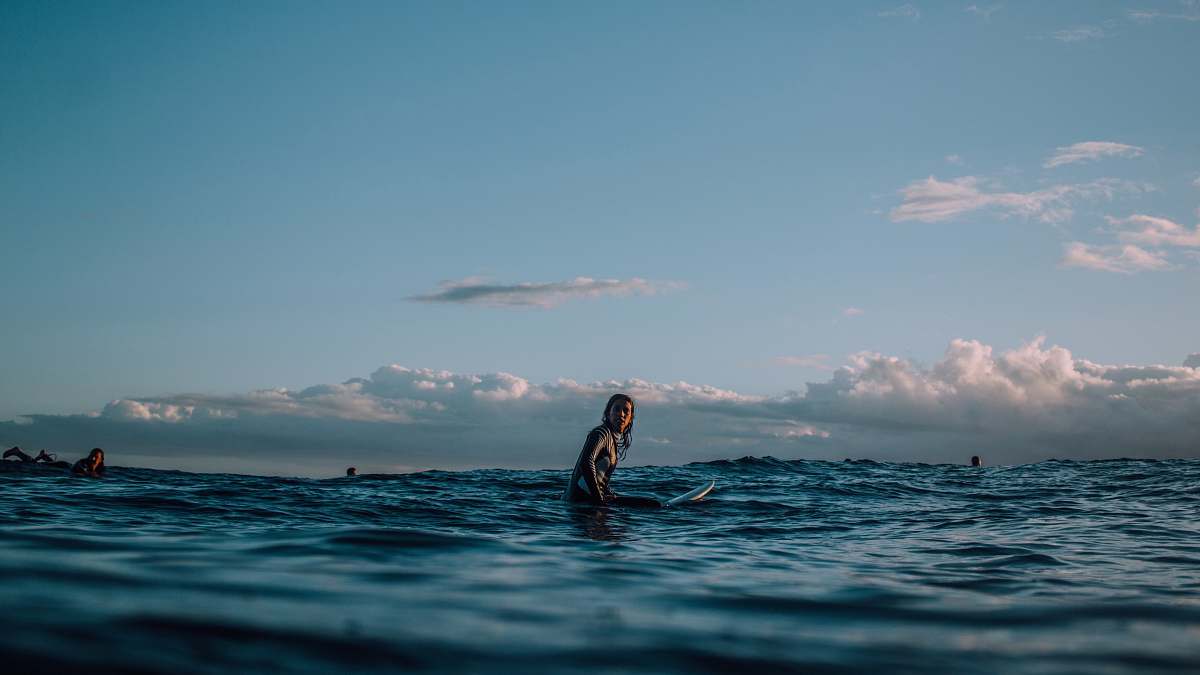 ripple person sitting on surfboard surrounded by blue ocean during daytime blue