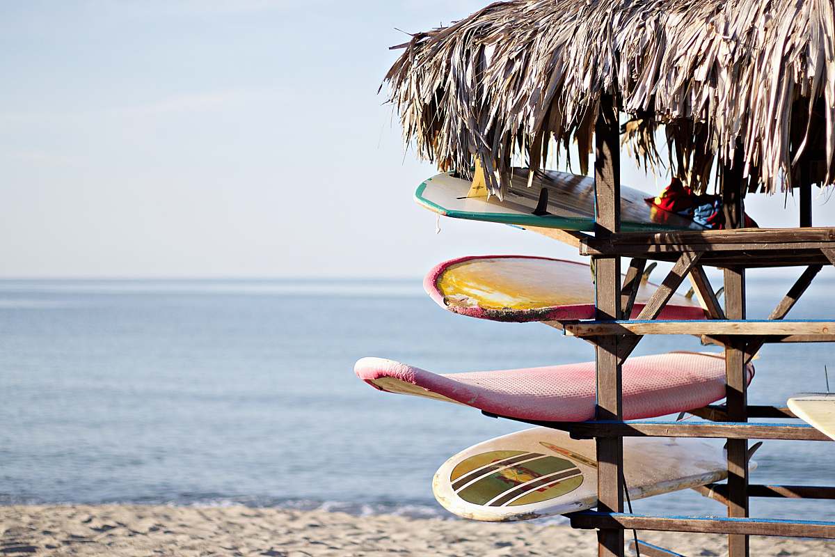 sea red and white surfboard in brown wooden rack summer
