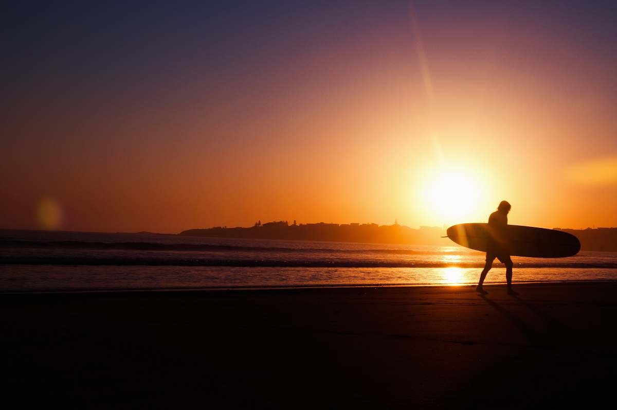 ocean silhouette of man holding surfboard near seashore during sunset surf