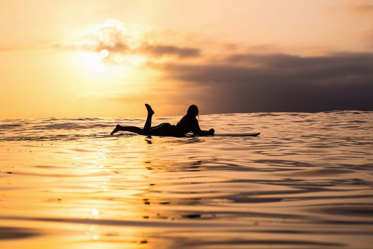 water silhouette of woman lying on surfboard at the sea surf