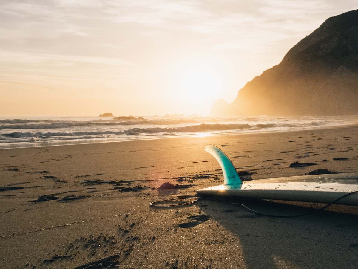 ocean surfboard on brown sand beside ocean during sunset nature