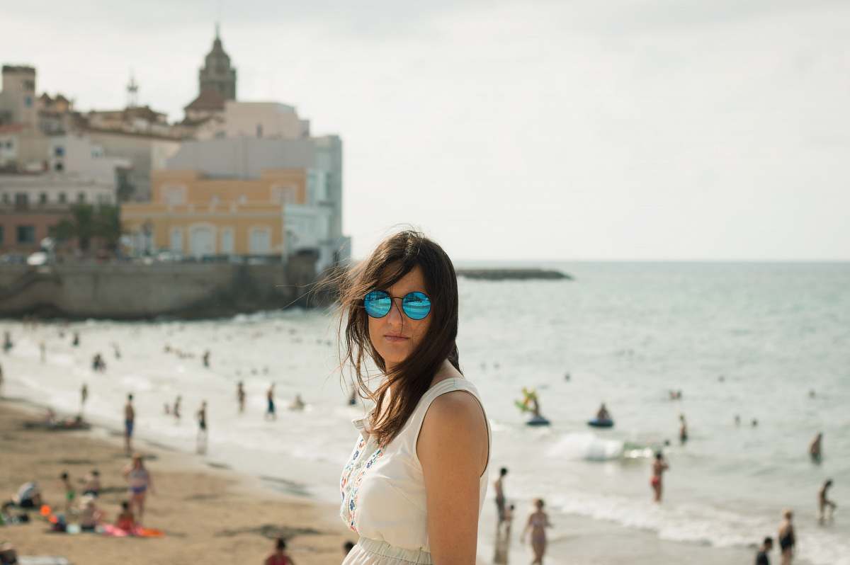 coast woman in white sleeveless top near seashore people