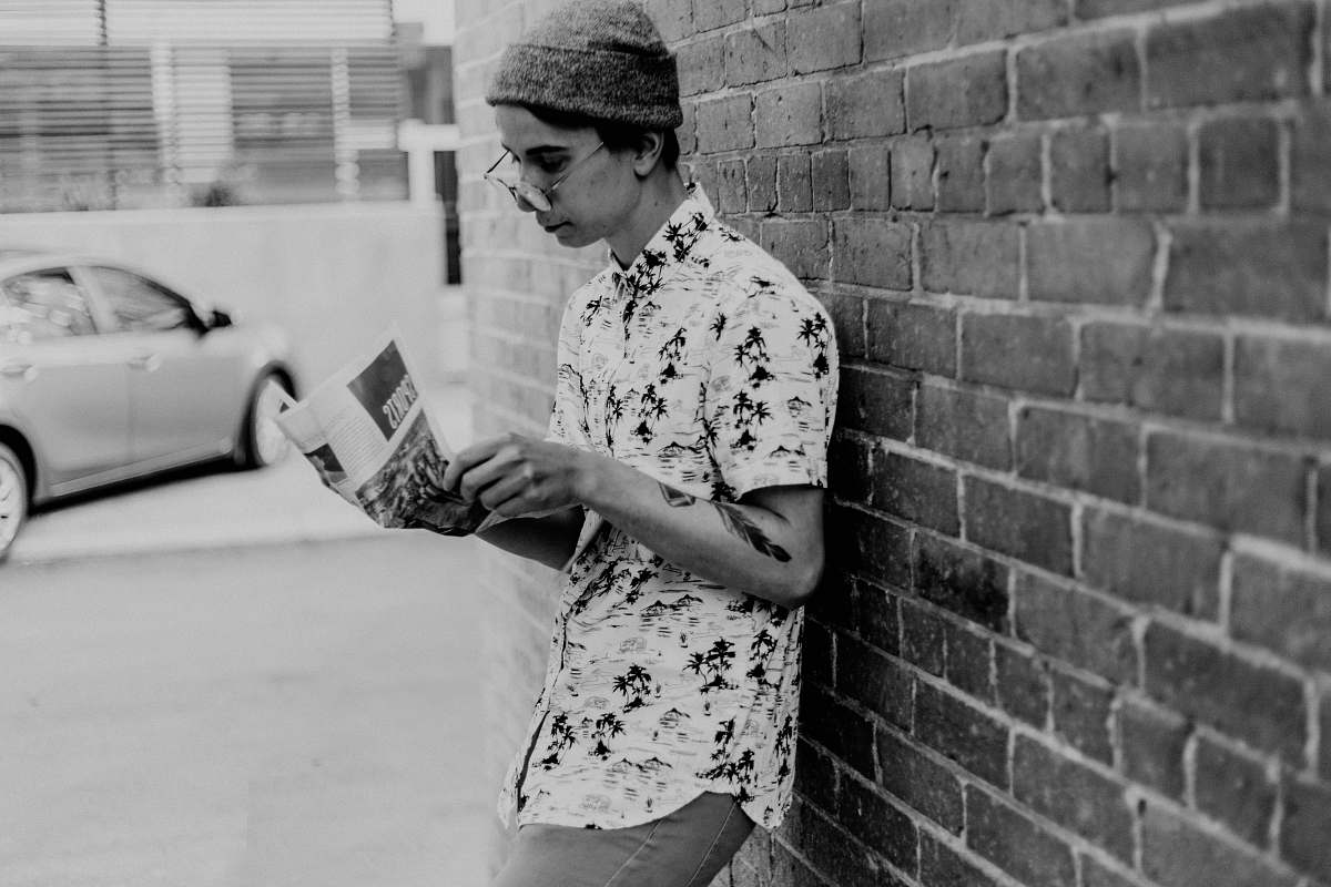 brick grayscale photo of man leaning on wall transportation