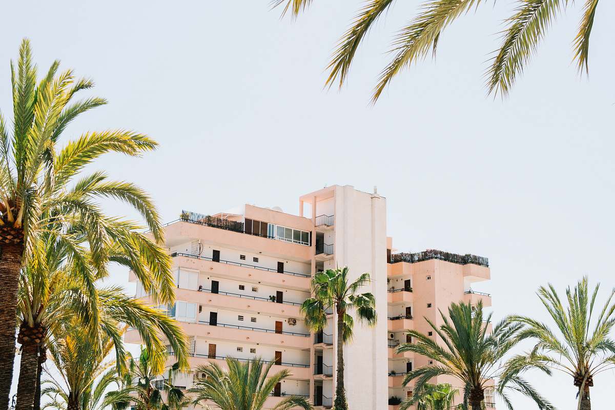 spain white concrete building beside green palm tree under white sky during daytime hotel