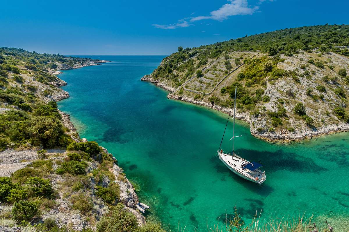 blue aerial photography of white boat near body of water between green mountain during daytime yacht