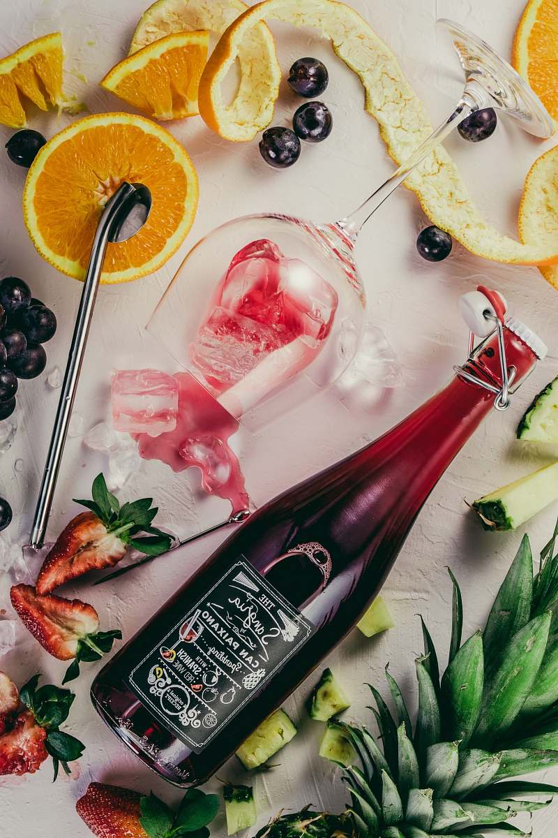 fruit flat-lay photograph of sliced fruits, swing top bottle, and wine glass pineapple