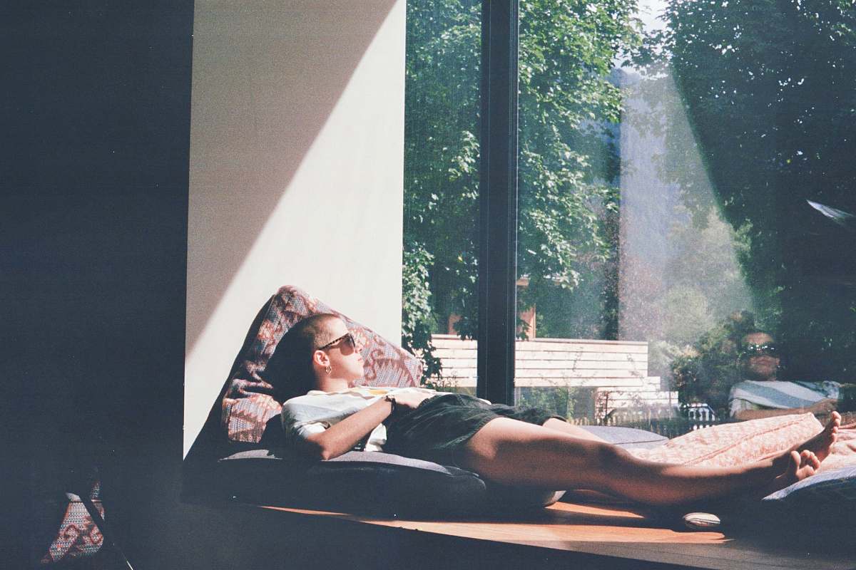 people man lying on cushion beside glass window person
