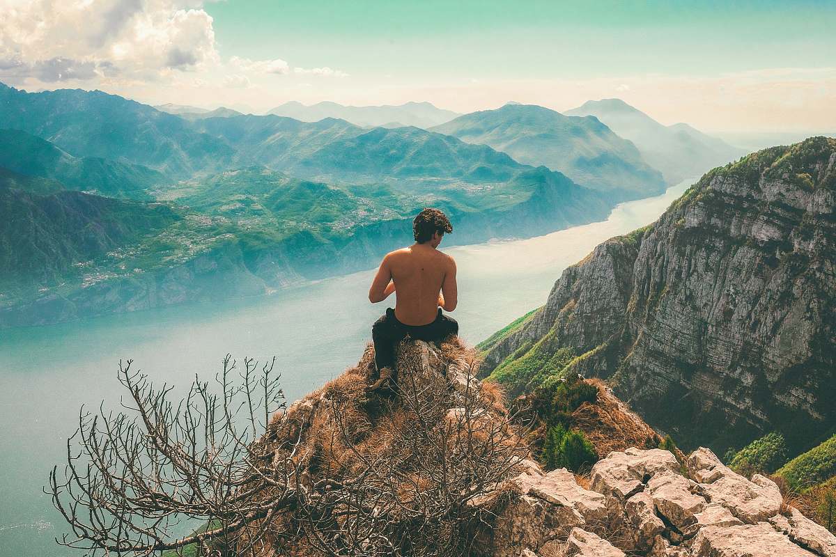 man man seating on top of cliff in front of mountains italy