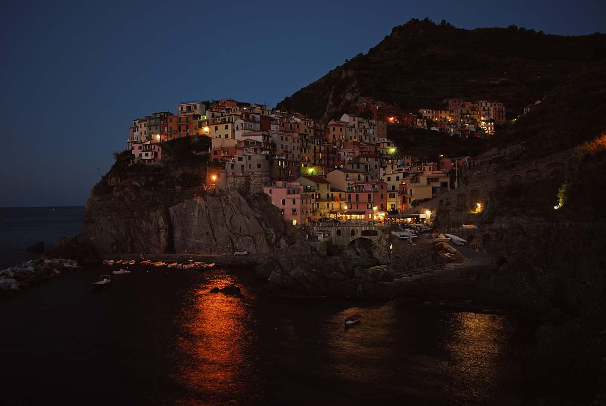 village concrete houses on rocky hill beside large body of water during nighttime town