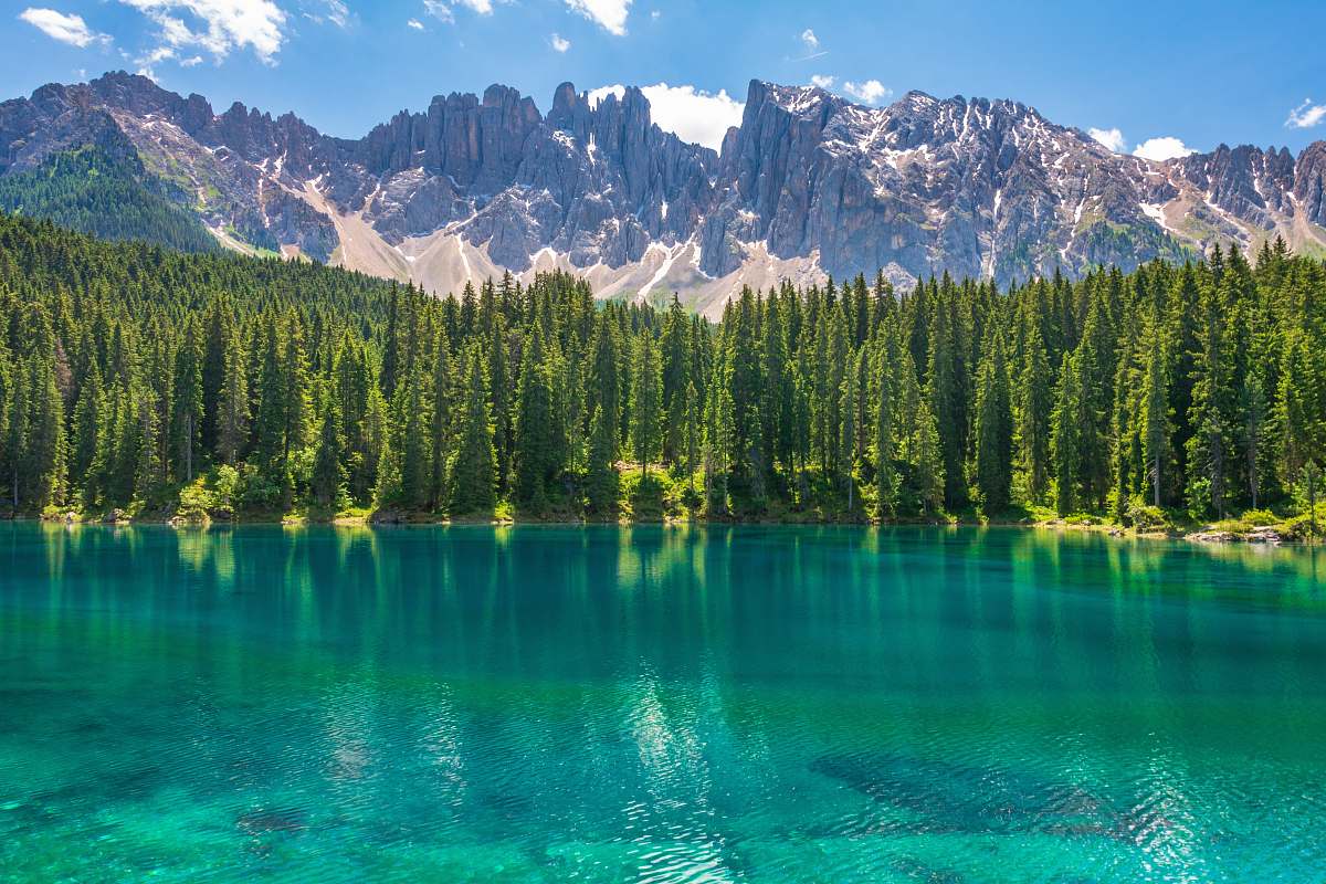 water green grasses near body of water with mountain range in vicinity lake
