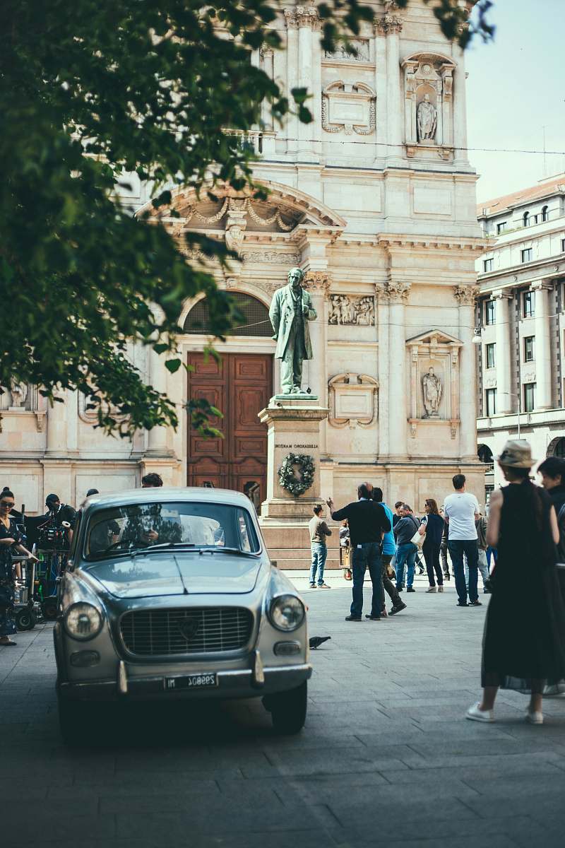 people vehicle surrounded by people near standing man statue during daytime car