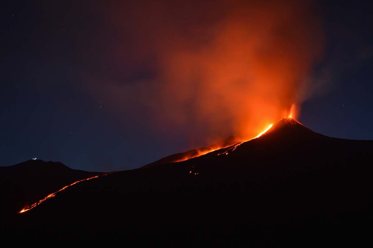 eruption black mountain with flowing lava at nighttime italy