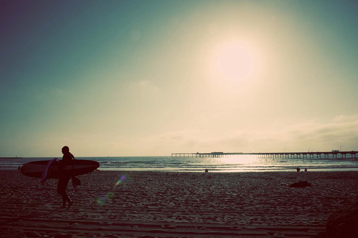 surf person carrying surfboard near seashore surfer