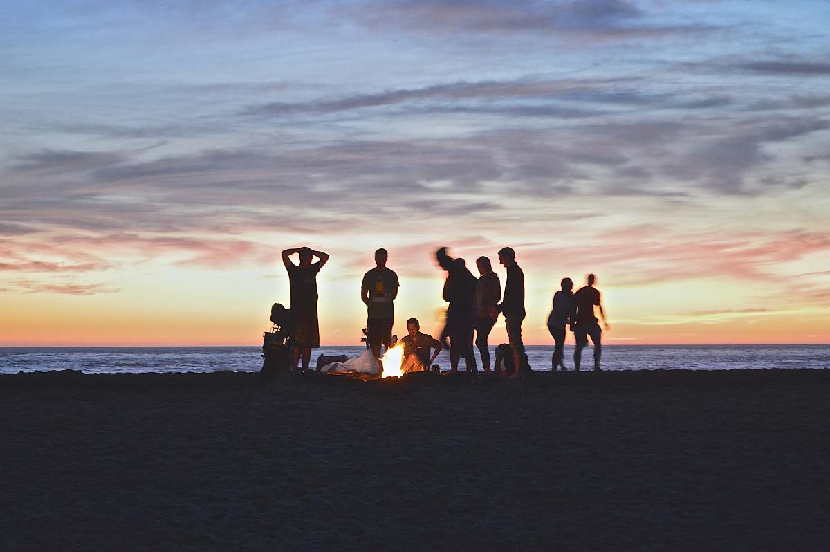 sunset group of people setting up campfire beach