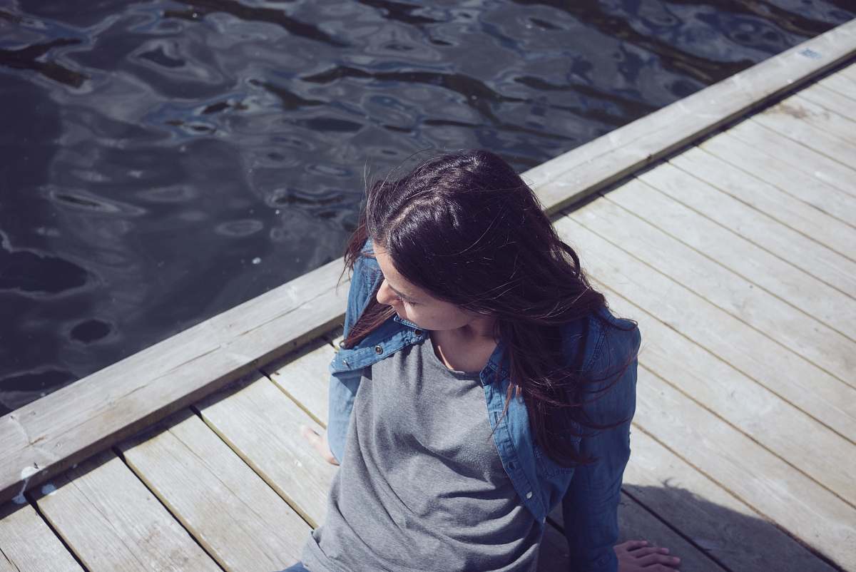 person woman in grey top seating on dock during daytime human