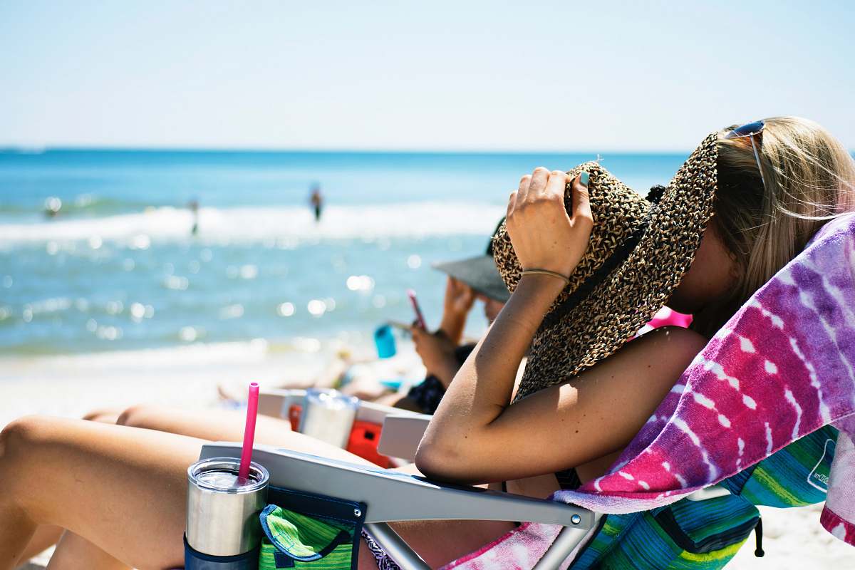 person woman lying on sun lounger covering her face with straw hat near sea human