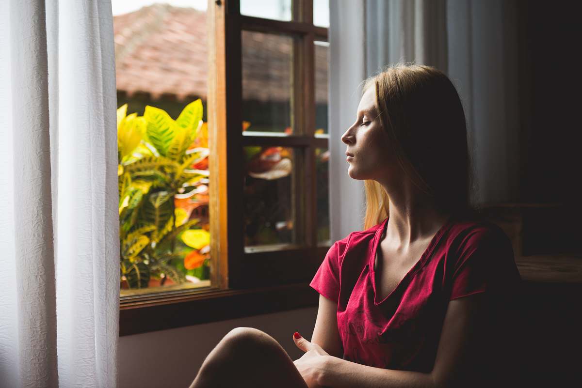 human woman sitting near open window plant