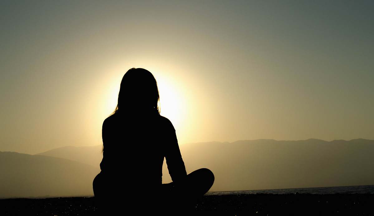 human woman sitting on sand meditation