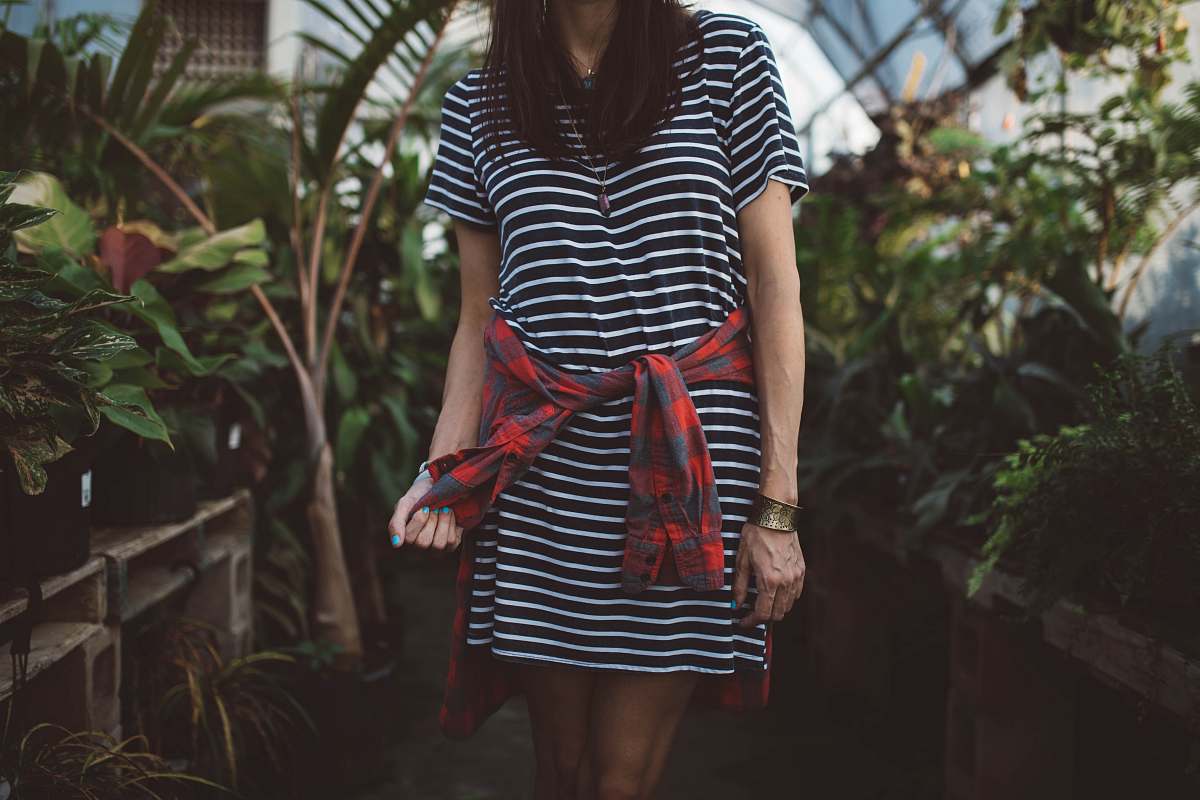 person woman wearing black and white striped dress standing in isle near green plants plant