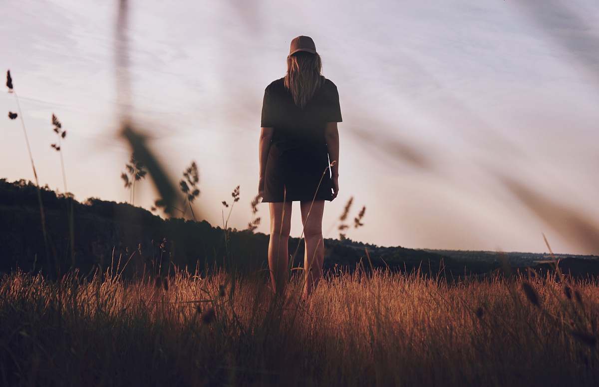 person worm's view photography of woman standing on grass field faceless