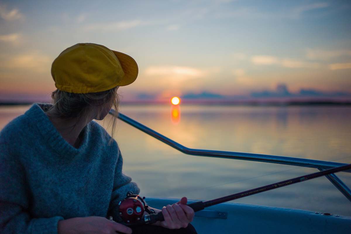 fishing man holding black fishing rod while facing body of water human
