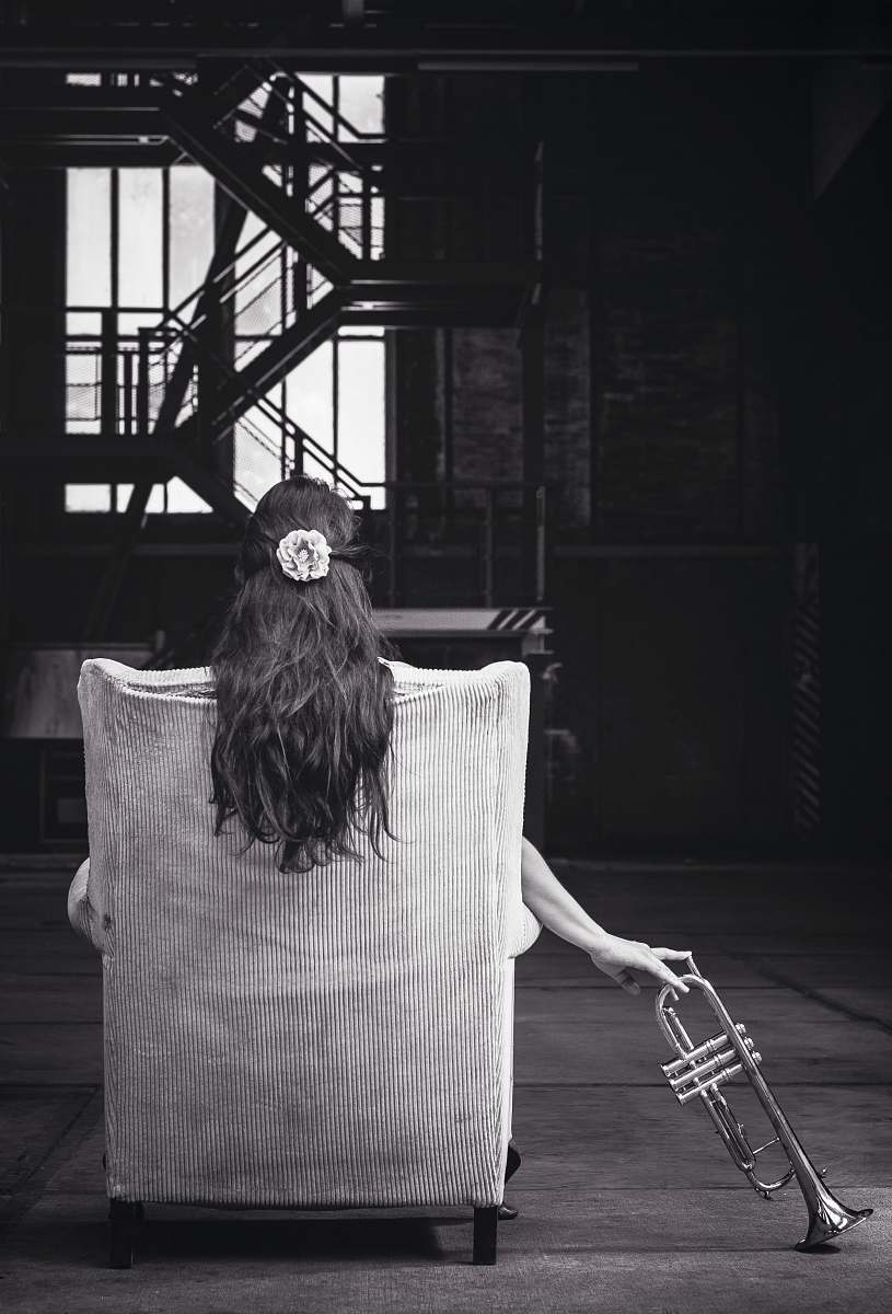 black-and-white woman sitting on chair holding trumpet music