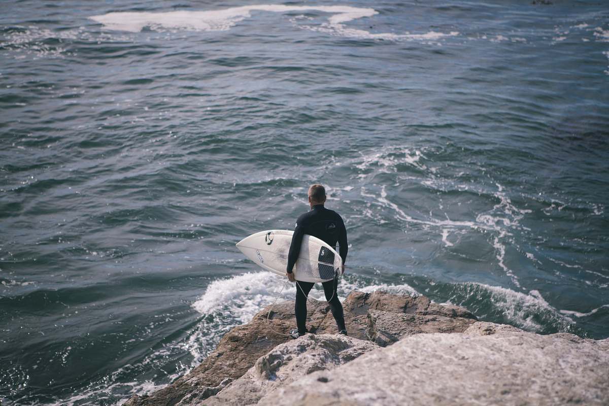 ocean man holding surfboard standing in front of sea person