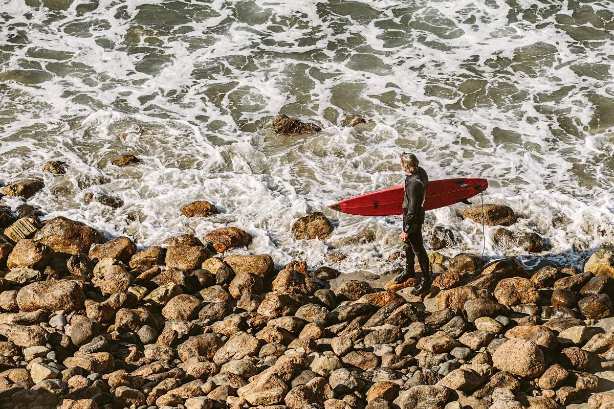 water person holding surfboard near seashore during daytime ocean