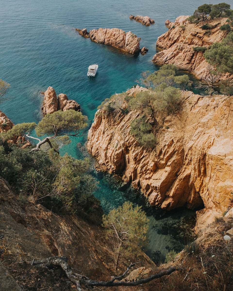 promontory bird's-eye photography of boat near rock formations cliff