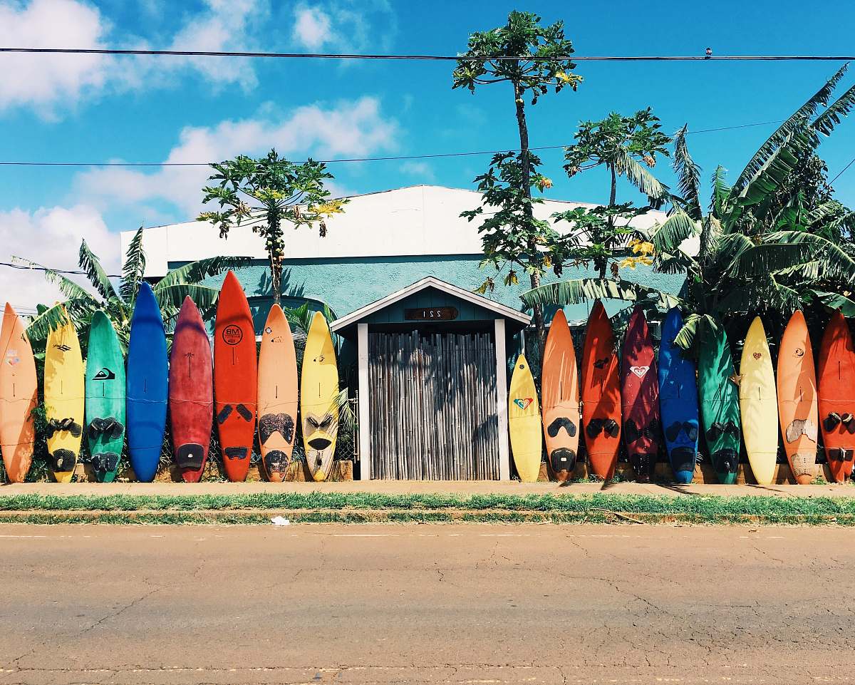 surfing blue and white house surrounded by surfboards during daytime surfboard