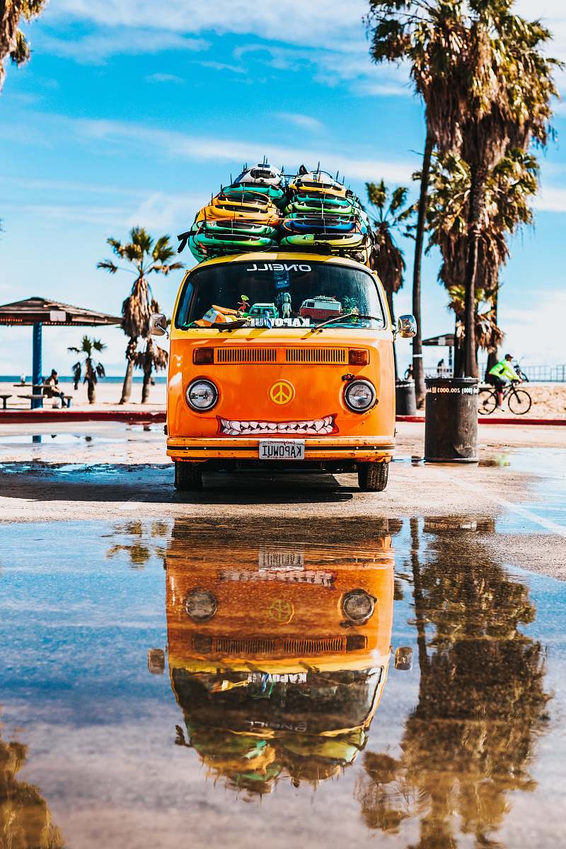 car orange van with surfboard on top beach