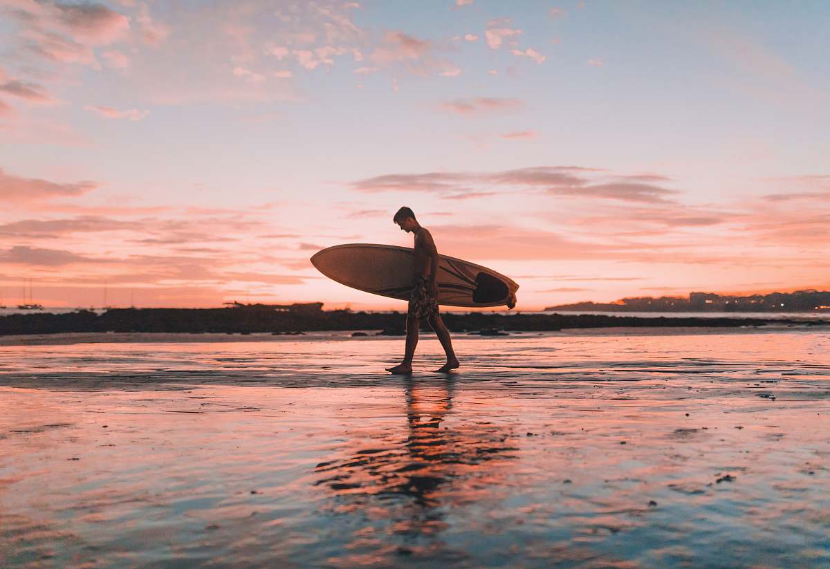 water man holding surfboard walking near seashore surfboard