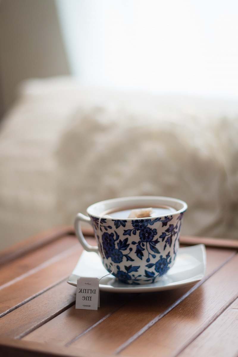 cup white and blue floral teacup with tea bag in saucer in tilt shift photography drink