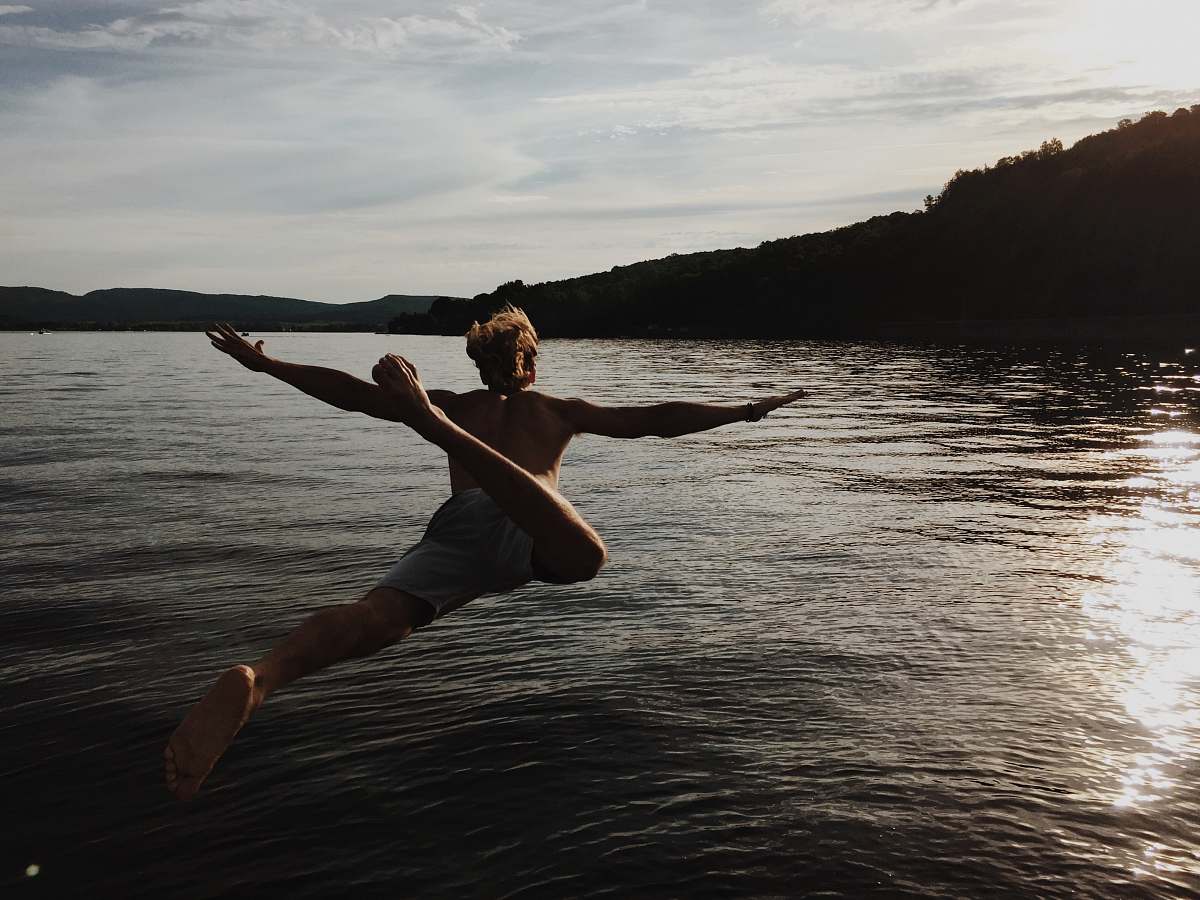 stretch person jumping to body of water lake