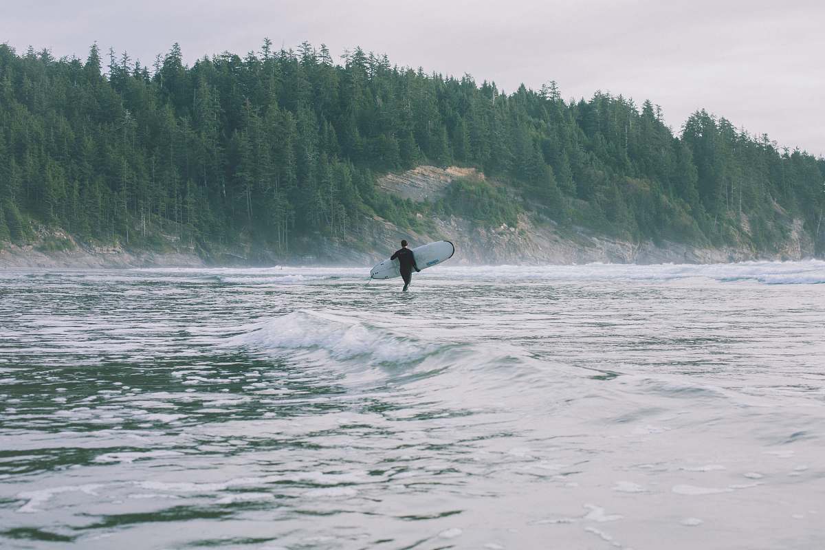 surfboard person walking on shore while holding surfboard during daytime grey