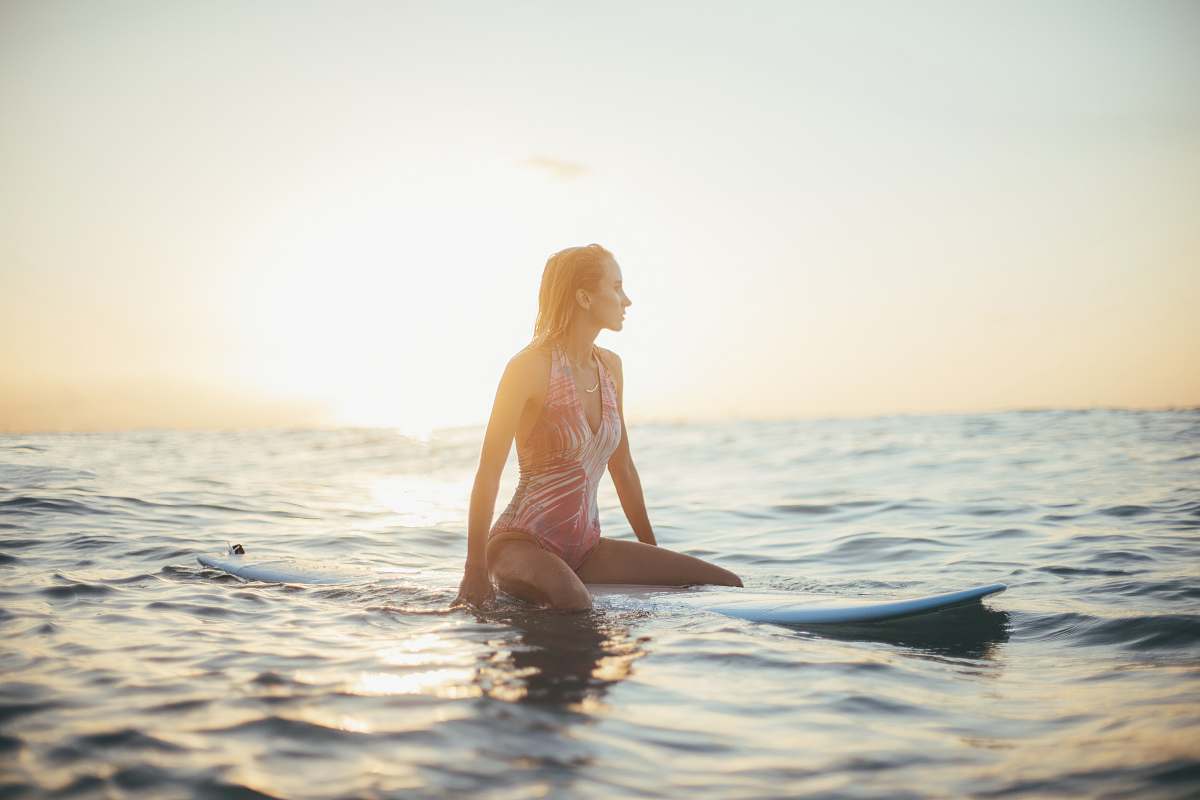 bikini woman riding a blue surfboard in a body of water clothing