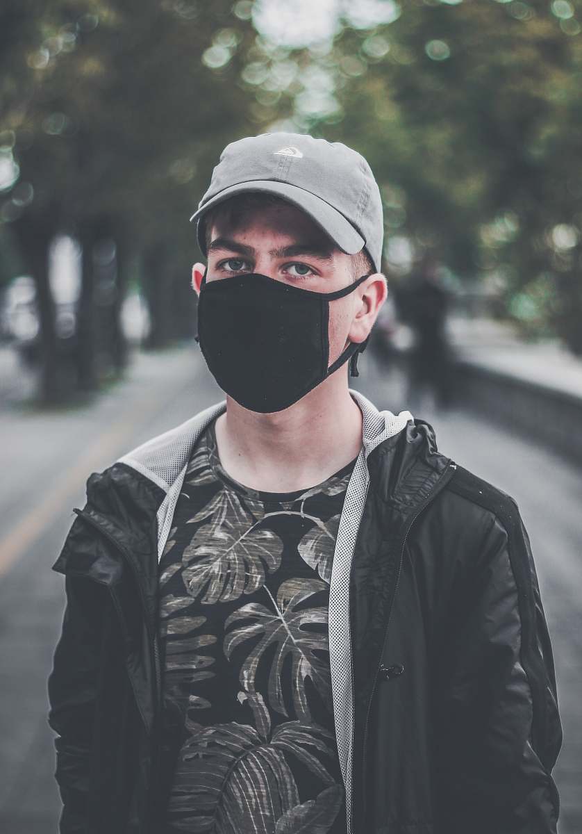 human man wearing black face mask on park during daytime person