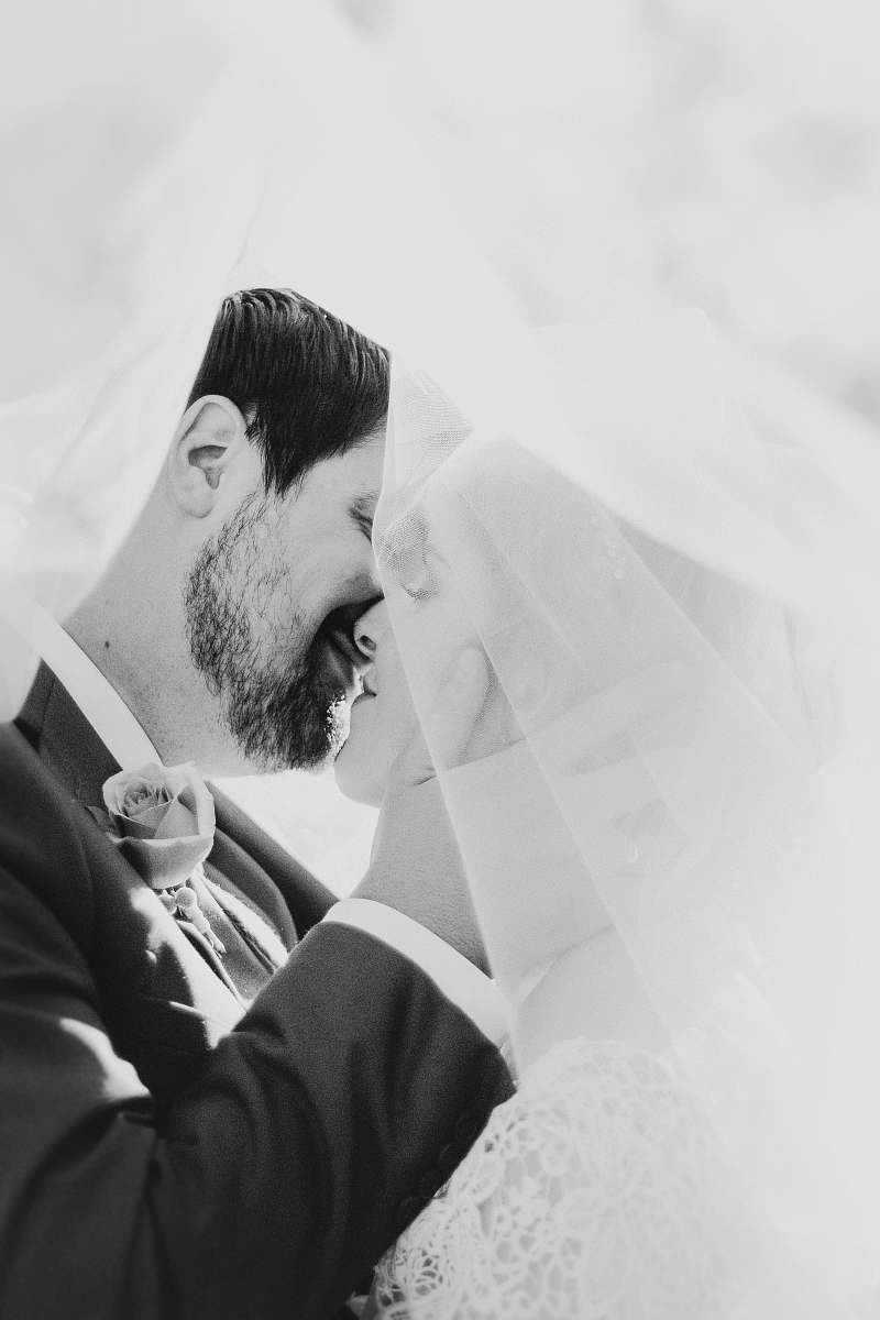 wedding bride and groom kissing each other veil