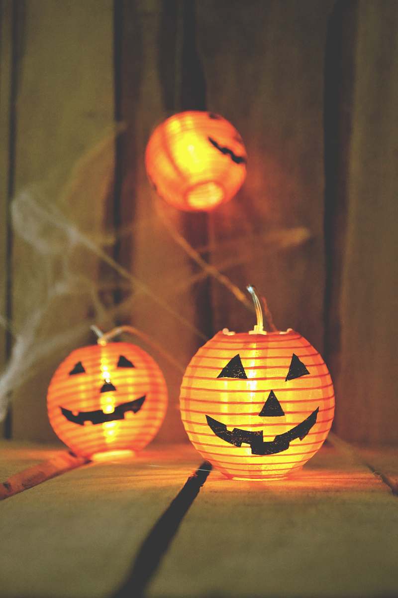 pumpkin three jack-o-lantern lamps on beige wooden board autumn