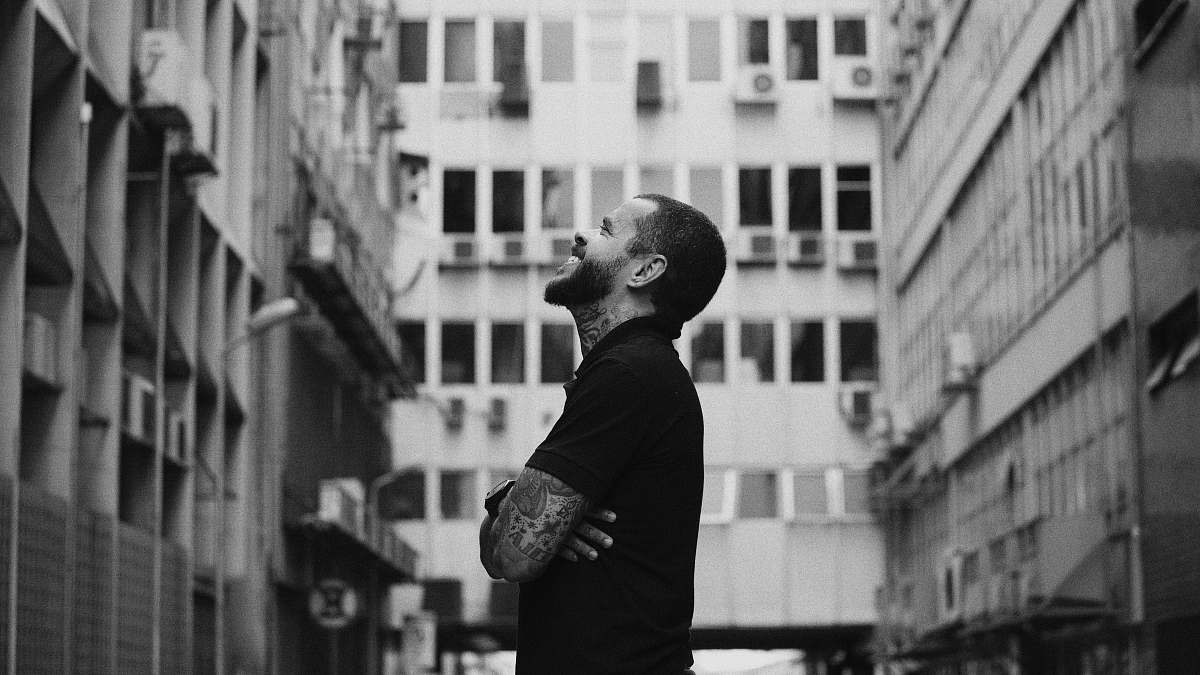 black-and-white grayscale photo of man standing near building urban
