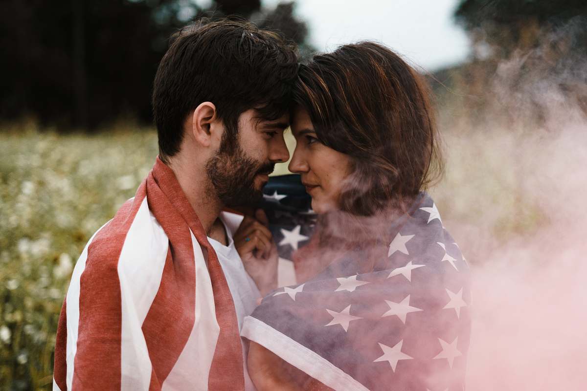 person man standing in front of woman covered with U.S.A. flag people
