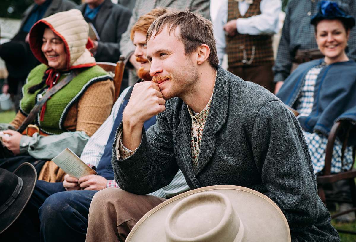 people man wearing black coat sitting beside man in blue vest during daytime man