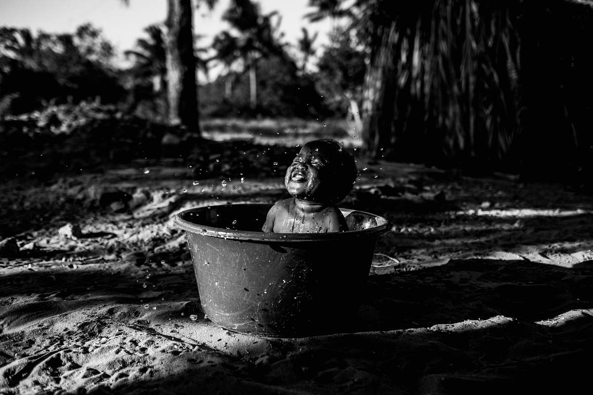 person topless baby smiling and sitting on pail black-and-white