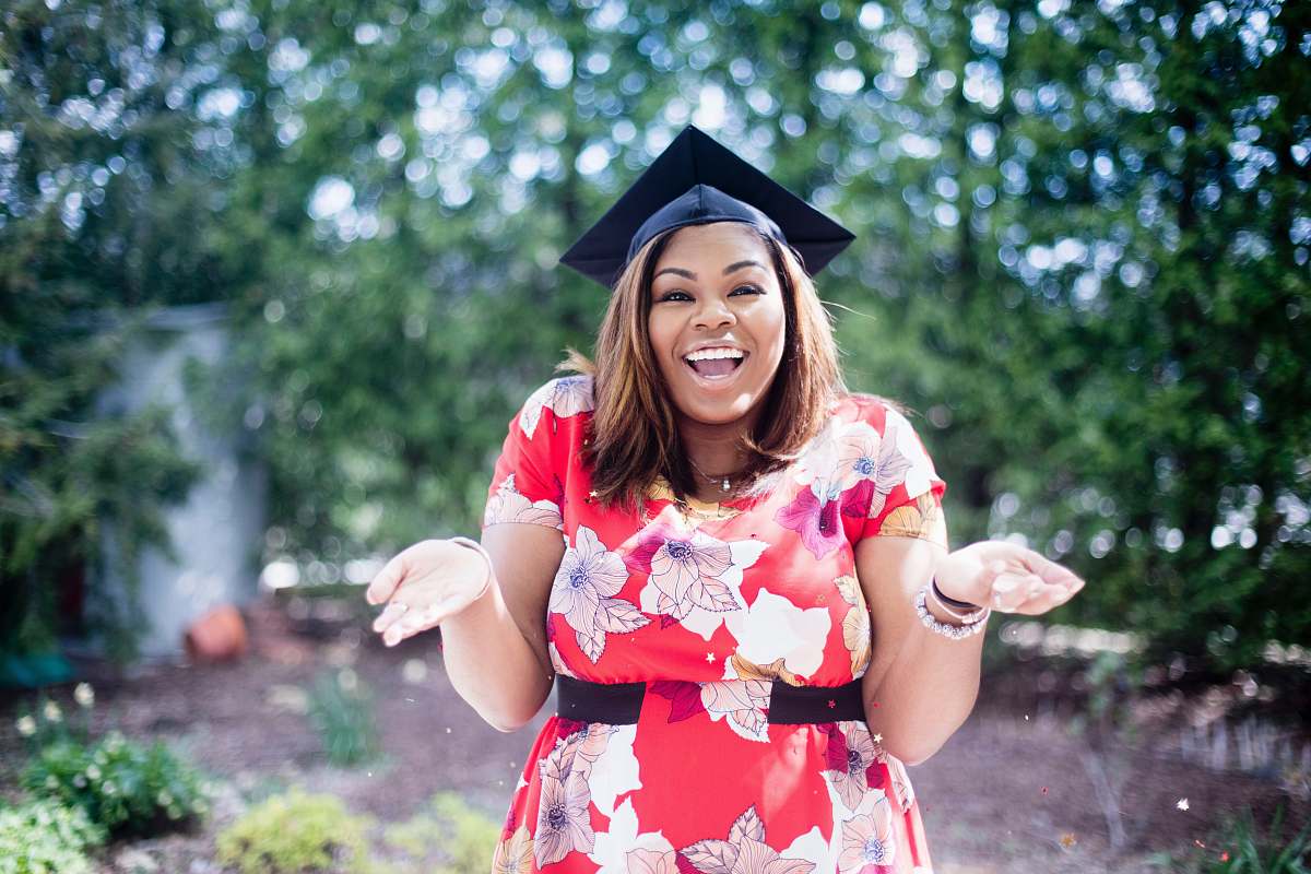 people woman wearing academic hat standing in garden showing palm at daytime woman